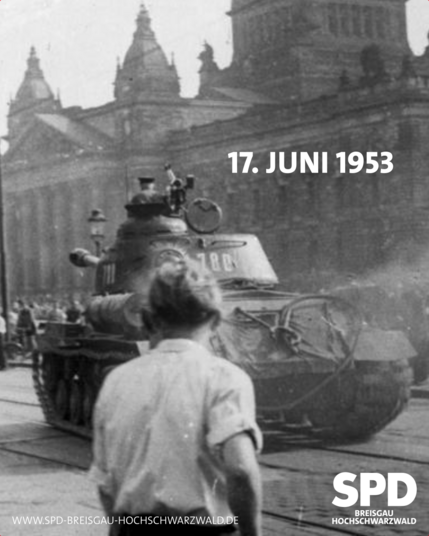Historische Aufnahme von 1953. Man sieht einen Mann von hinten. Ein Panzer fährt vorbei. Im Hintergrund eine Menschenmenge. Schwarz-weiß-Foto.